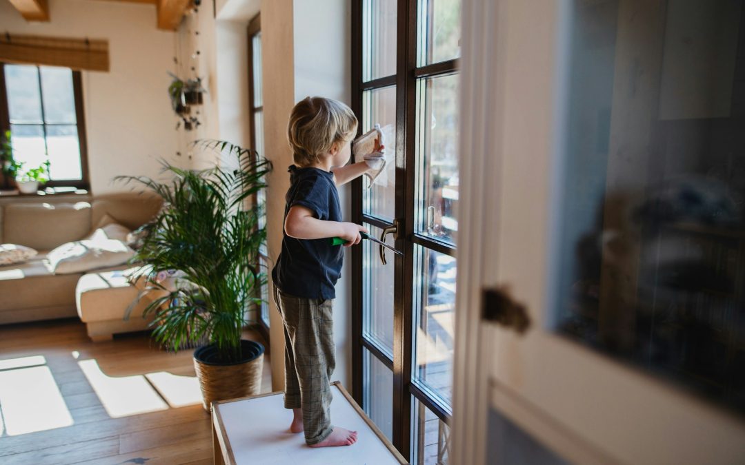 kid cleaning glass windows at home